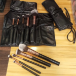 Set of makeup brushes displayed neatly alongside a stylish leather bag, showcasing their elegant design and soft bristles.